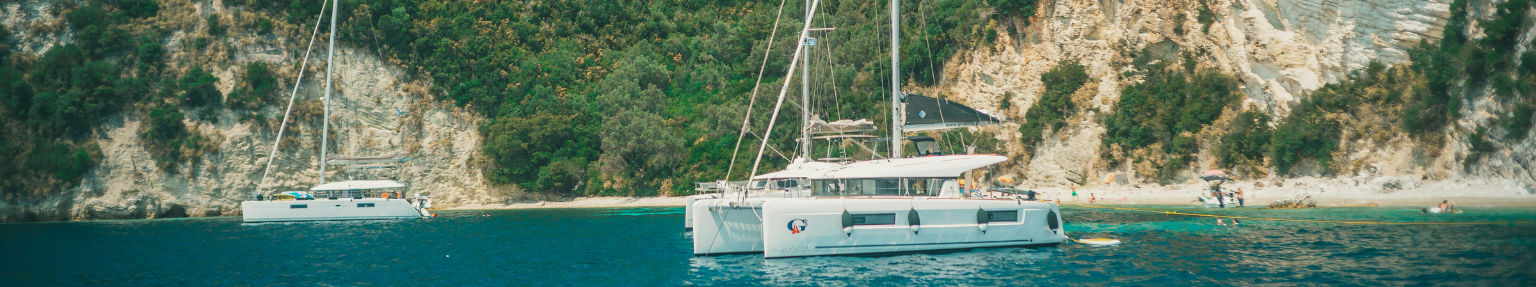Catamarano con equipaggio all'ancora in una baia turchese del Mediterraneo, hostess serve il pranzo nel pozzetto, noleggio yacht con equipaggio Mediterraneo, Borrow A Boat