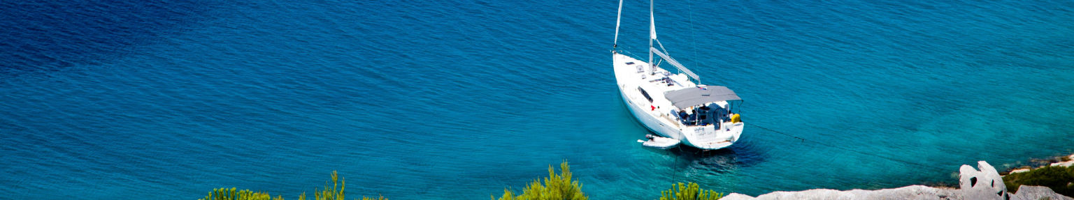 Sailboat with skipper at the helm anchored off Elba island, Tuscany, Borrow A Boat skippered yacht charter