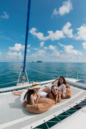 People sitting in the bow nets of a catamaran