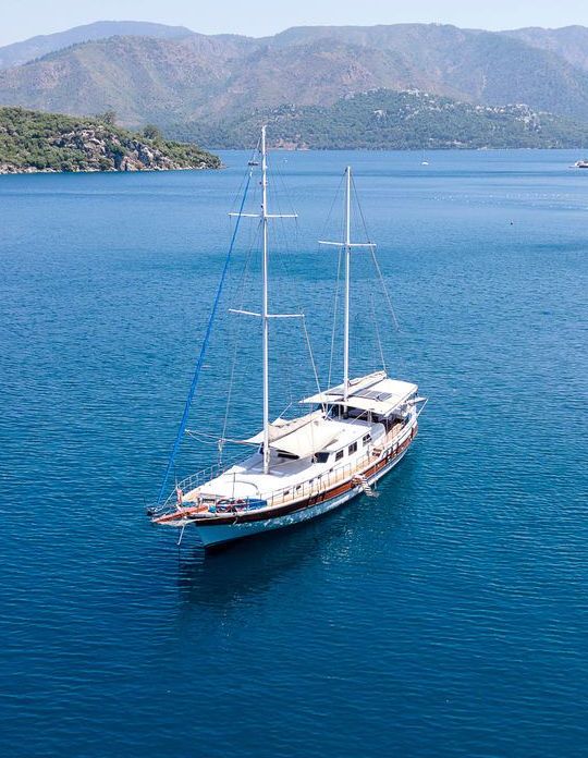 A gulet in the water in front of a mountain range