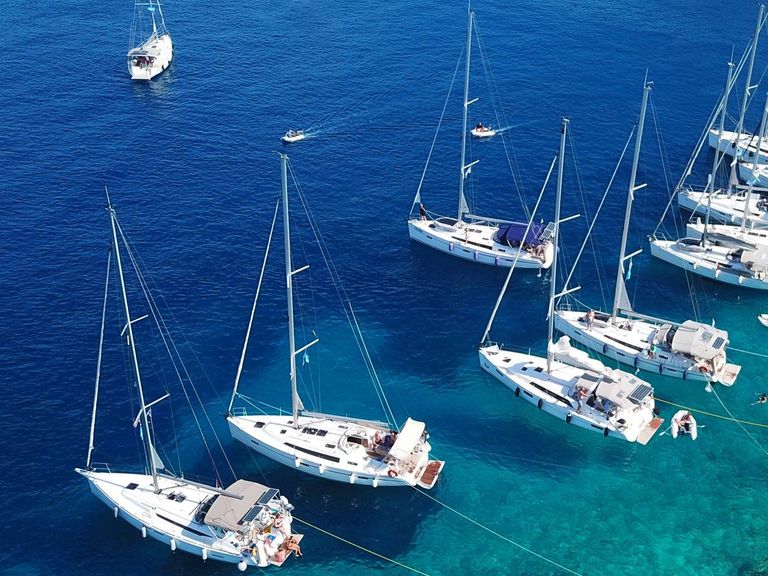 Sailboats anchored with shore lines in Greece