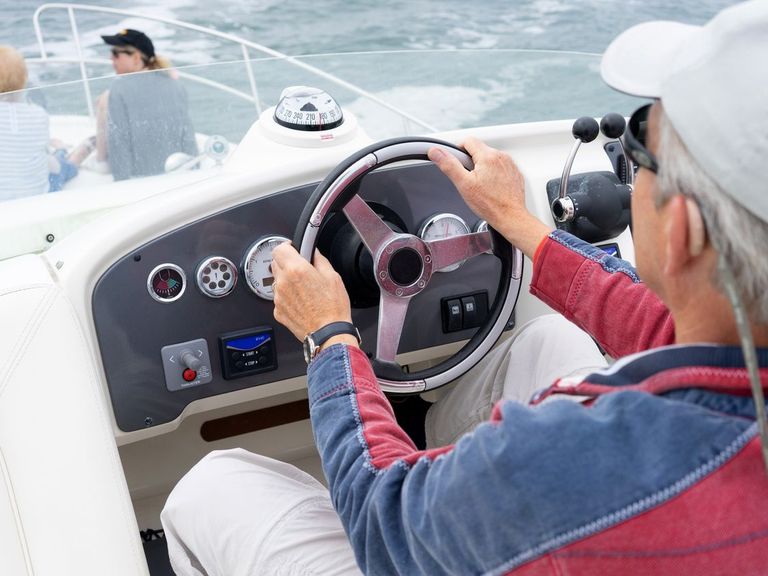 Sailor at helm of a motoryacht with fly bridge